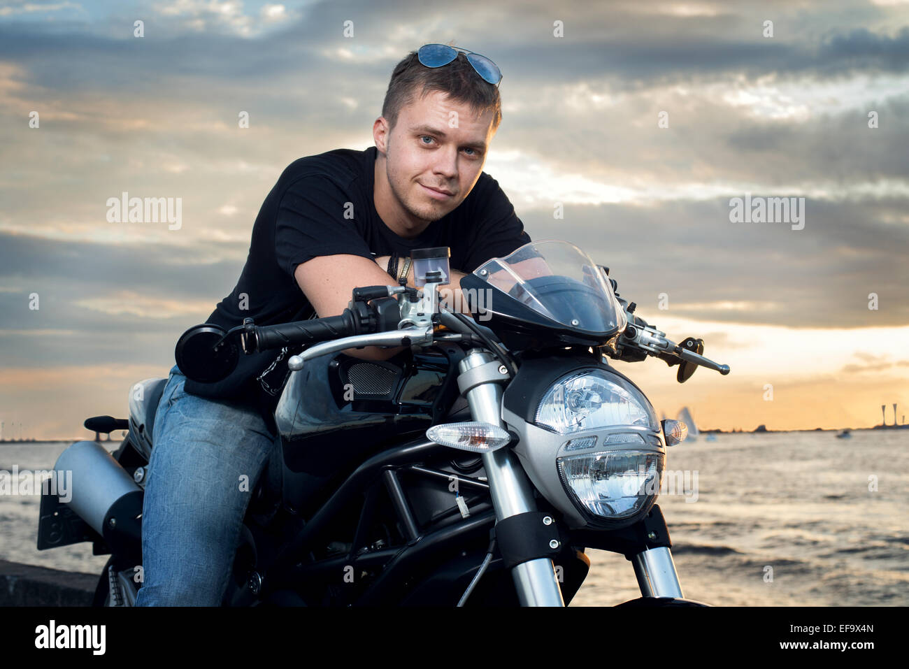 Freundlicher Kerl auf einem Motorrad in die Kamera Lächeln Stockfoto