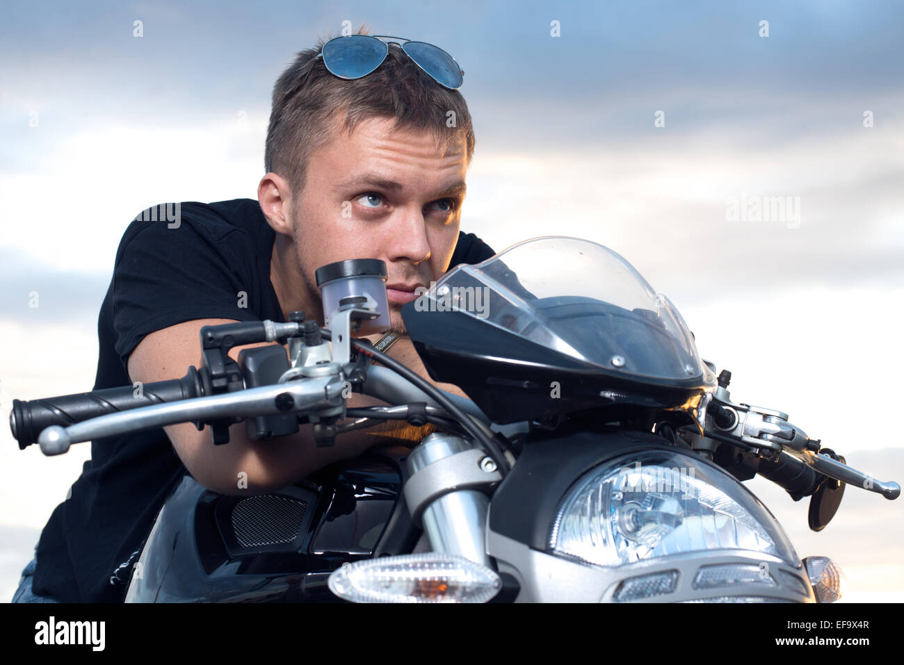 junger Mann mit einem hartnäckigen Look stützte sich auf das Lenkrad über sein Motorrad Stockfoto