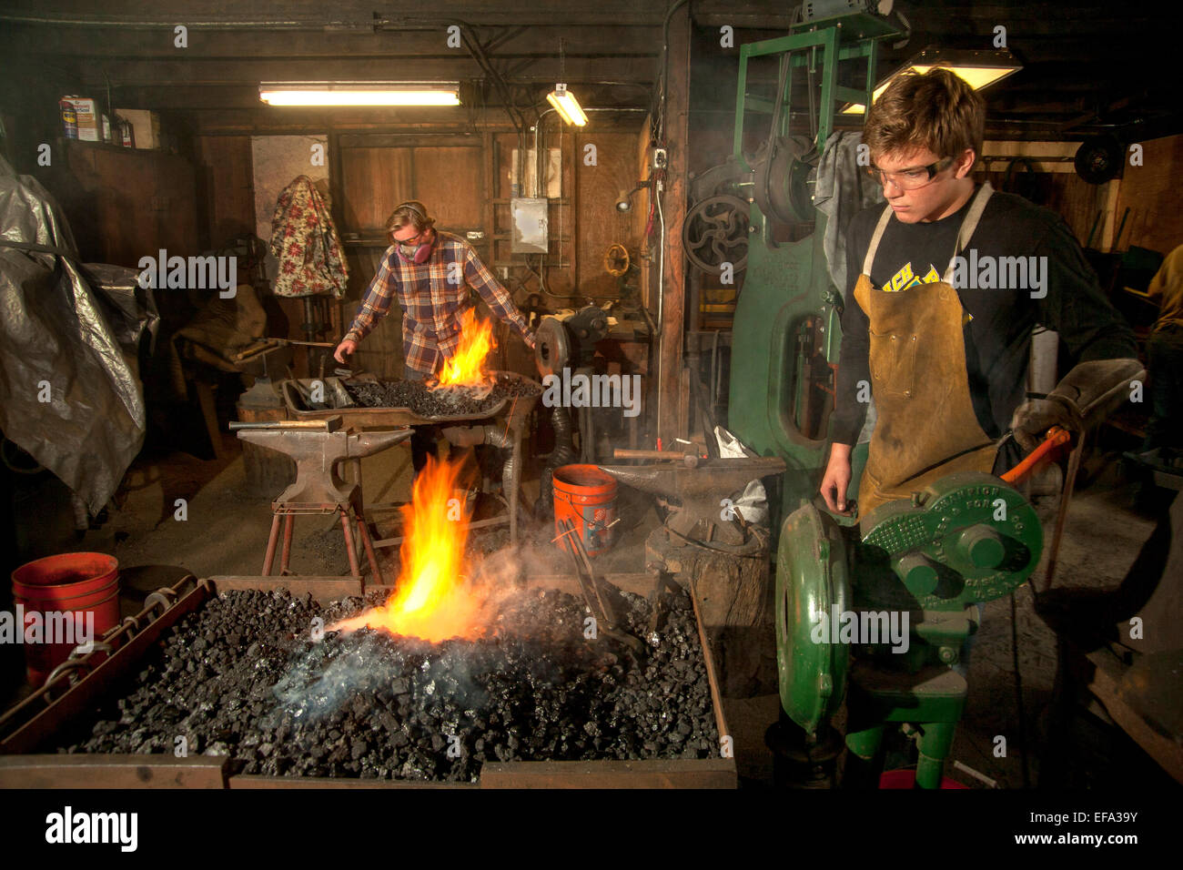 Flammen steigen, da moderne Amateur-Schmiede ihre traditionellen Kohle heizen auf eine Schmiede 1890-Ära an das Orange County Heritage Museum in Santa Ana, CA. Hinweis Schutzbrille, Handschuhe, Schürzen und Atemschutz schmiedet Stockfoto