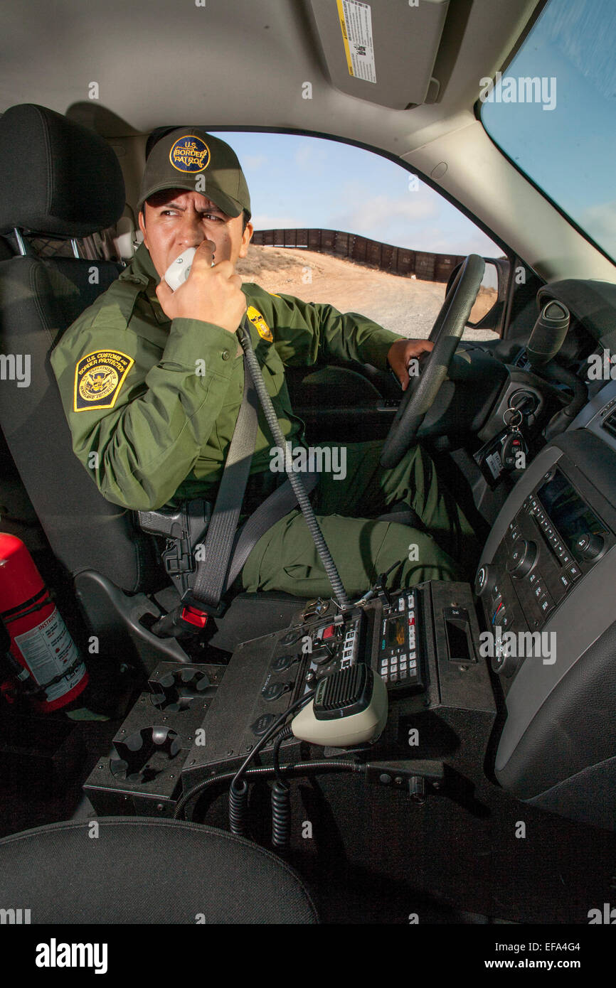 Bereich "Bunker Hill" von der U.S./Mexico Grenze in der Nähe von Tijuana, ein Hispanic Border Patrol Officer in seiner SUV-Gespräche über sein Radio mit Sitz Polizeiarbeit. Die Border Patrol ist Teil des US Department of Homeland Security. Hinweis Grenzzaun im Hintergrund. Stockfoto