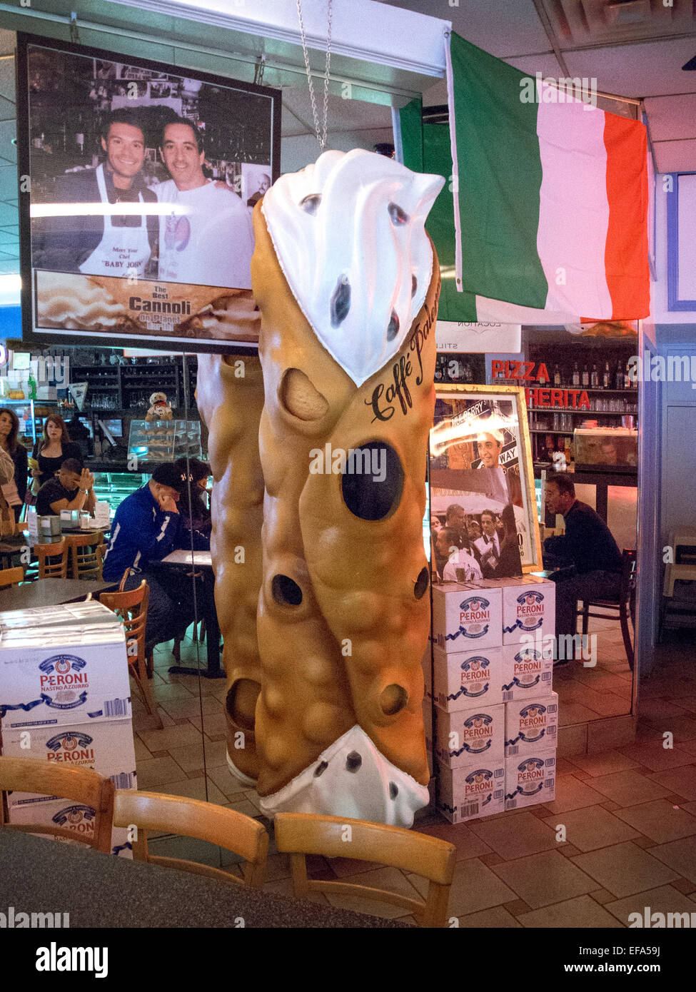 Ein riesiges Modell eines Canoli schmückt ein Restaurant im New Yorker Stadtteil Little Italy in Manhattan. Cannoli sind italienische Gebäck Desserts bestehend aus röhrenförmigen Muscheln von frittierten Teig, gefüllt mit einer süßen, cremigen Füllung in der Regel mit Ricotta-Käse. Beachten Sie die italienische Flagge. Stockfoto