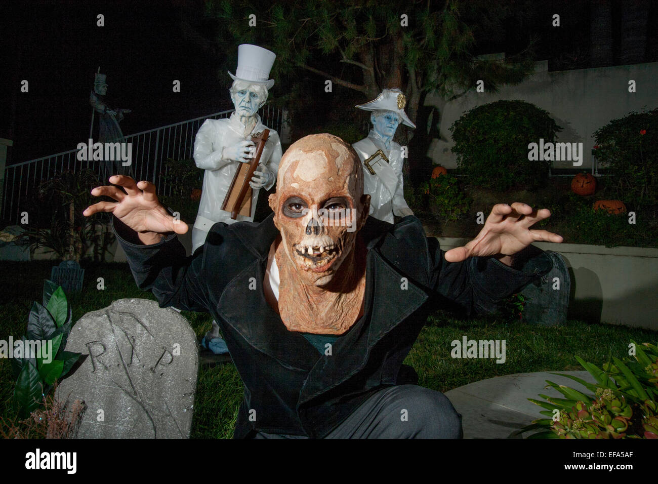 Mit einem Monster Schreck Maske bekommt ein junger Mann in den Geist der eine Halloween-Nacht "haunted Mansion" in Lake Forest, CA. Hinweis gespenstischen Figuren im Hintergrund. Stockfoto