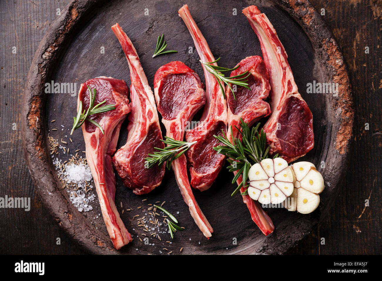 Rohes, frisches Lamm Rippen und würzigen Kräutern auf dunklem Hintergrund Stockfoto