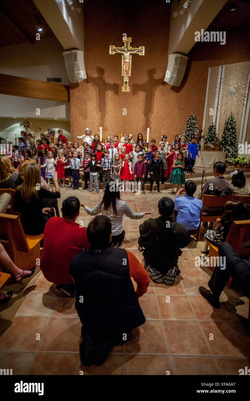 Gemischtrassig junge Kinder singen Weihnachtslieder während der Christmette am St. Timothy katholische Kirche, Laguna Niguel, CA. Hinweis Chorleiter. Stockfoto