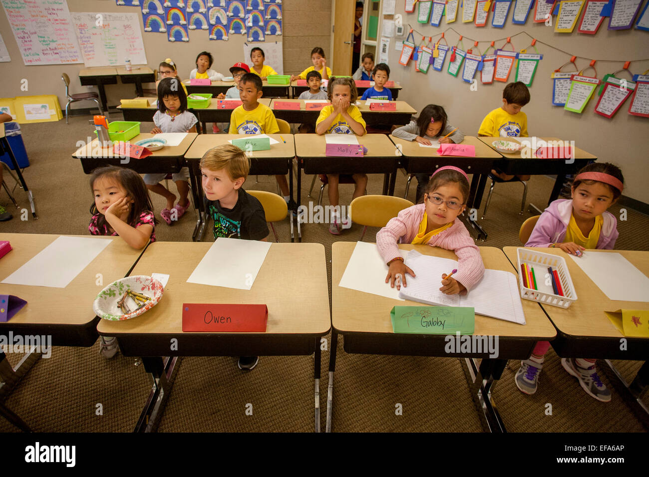 Gemischtrassig Grundschüler zeigen vielfältige Grad der Konzentration beim hören von ihrem Lehrer in einem Klassenzimmer in Irvine, CA. Beachten Sie die Aufsätze auf Wand angezeigt. Stockfoto