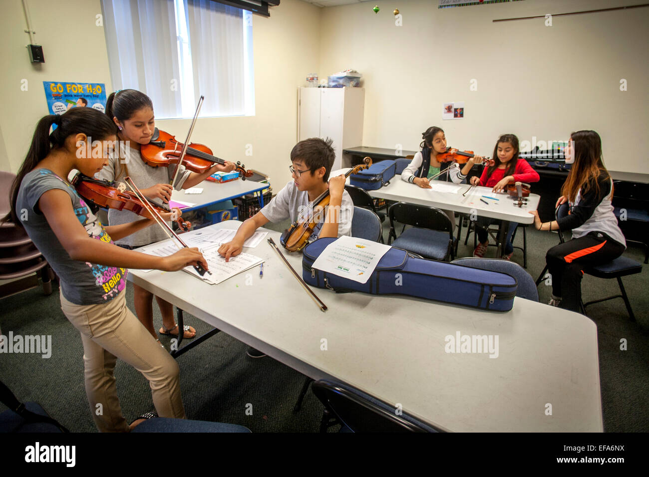 Asiatische Gymnasium Freiwilligen Musik Mentoren lehrt Violine Hispanic Teen Mädchen an einem Gemeindezentrum in Santa Ana, CA. Hinweis Noten. Stockfoto