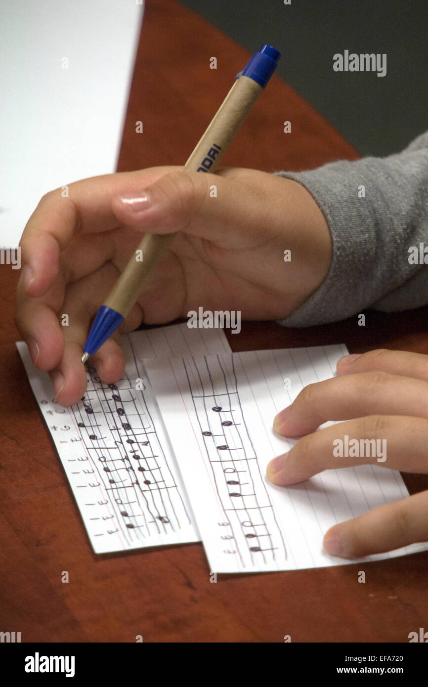 Asiatische Gymnasium Freiwilligen Musik Mentor schreibt die Noten in "Jingle Bells" beim Musikunterricht Hispanic Kindern ein Gemeindezentrum in Santa Ana, Kalifornien. Stockfoto