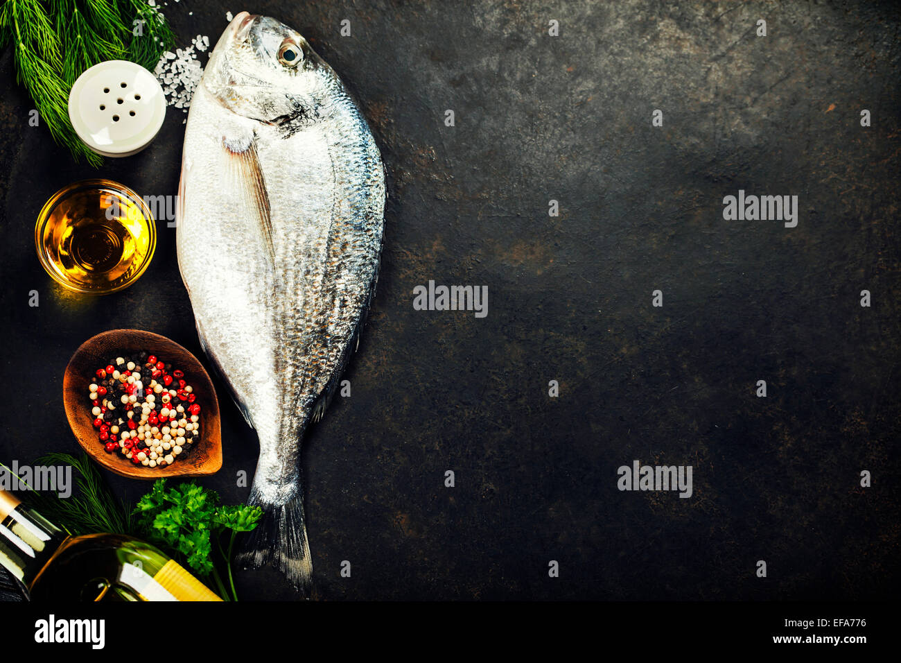 Köstlichen frischen Fisch auf dunkle Vintage-Hintergrund. Fisch mit aromatischen Kräutern, Gewürzen und Gemüse - gesunde Ernährung, Diät oder Kochen Stockfoto