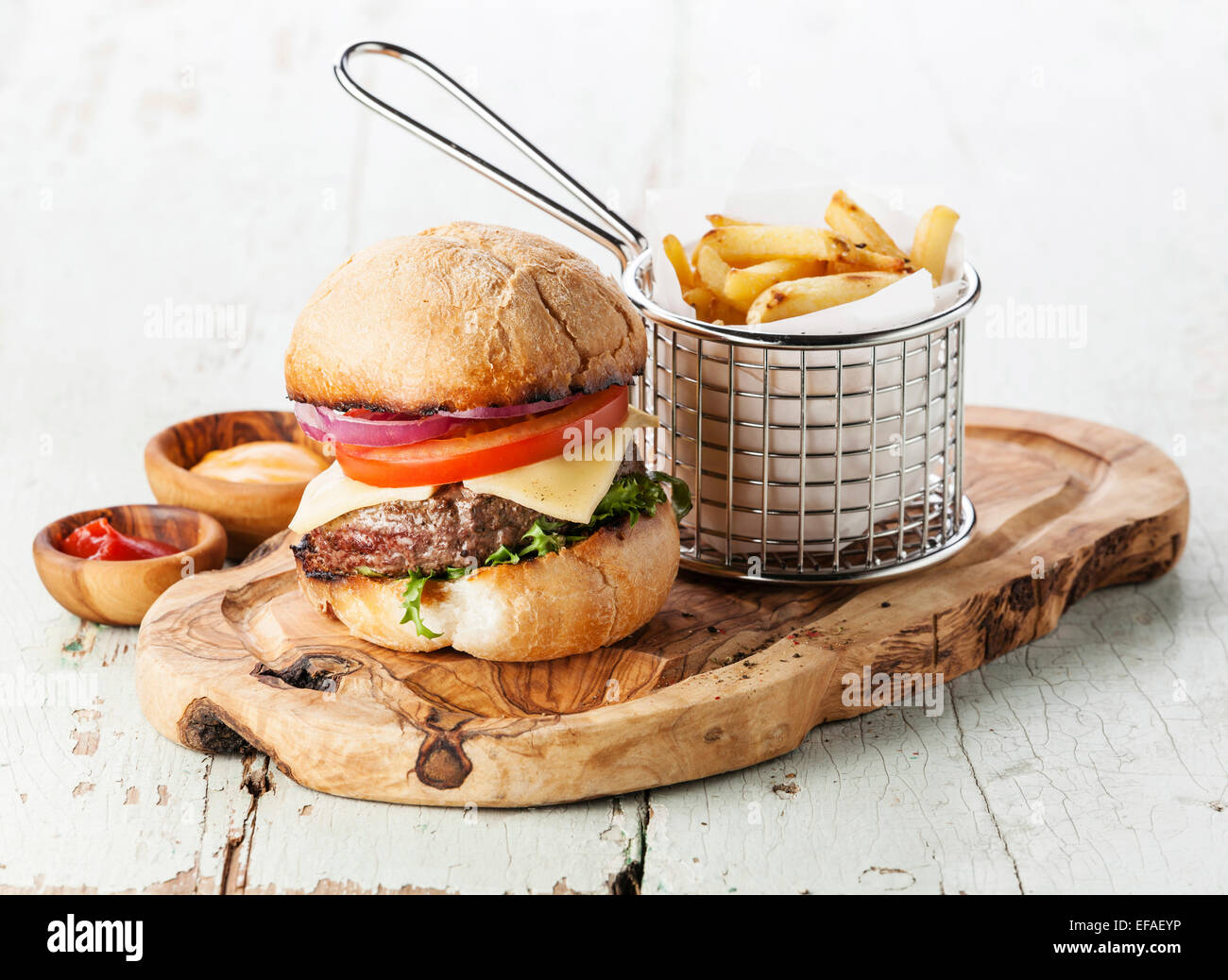 Burger mit Fleisch und Pommes frites im Korb auf hölzernen Hintergrund Stockfoto