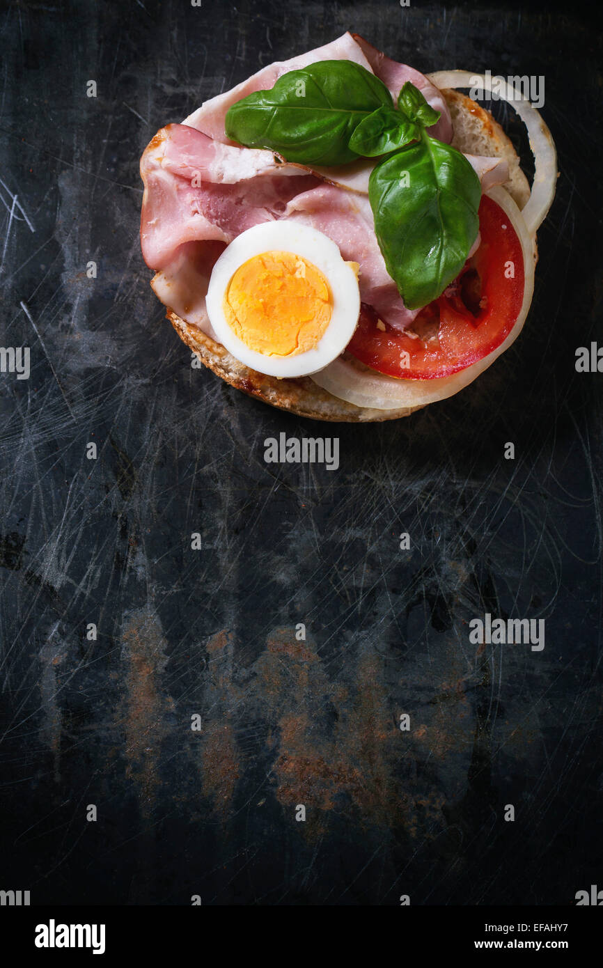 Sandwich mit Schinken, Eiern, Gemüse und Ketchup über schwarzen Metall Hintergrund. Ansicht von oben Stockfoto