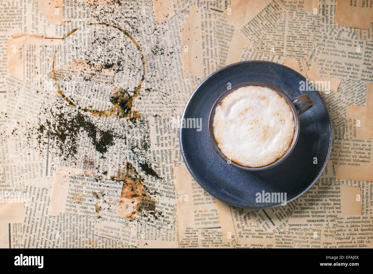 Blaue Keramik Tasse Cappuccino über alte Zeitung. Ansicht von oben. Stockfoto