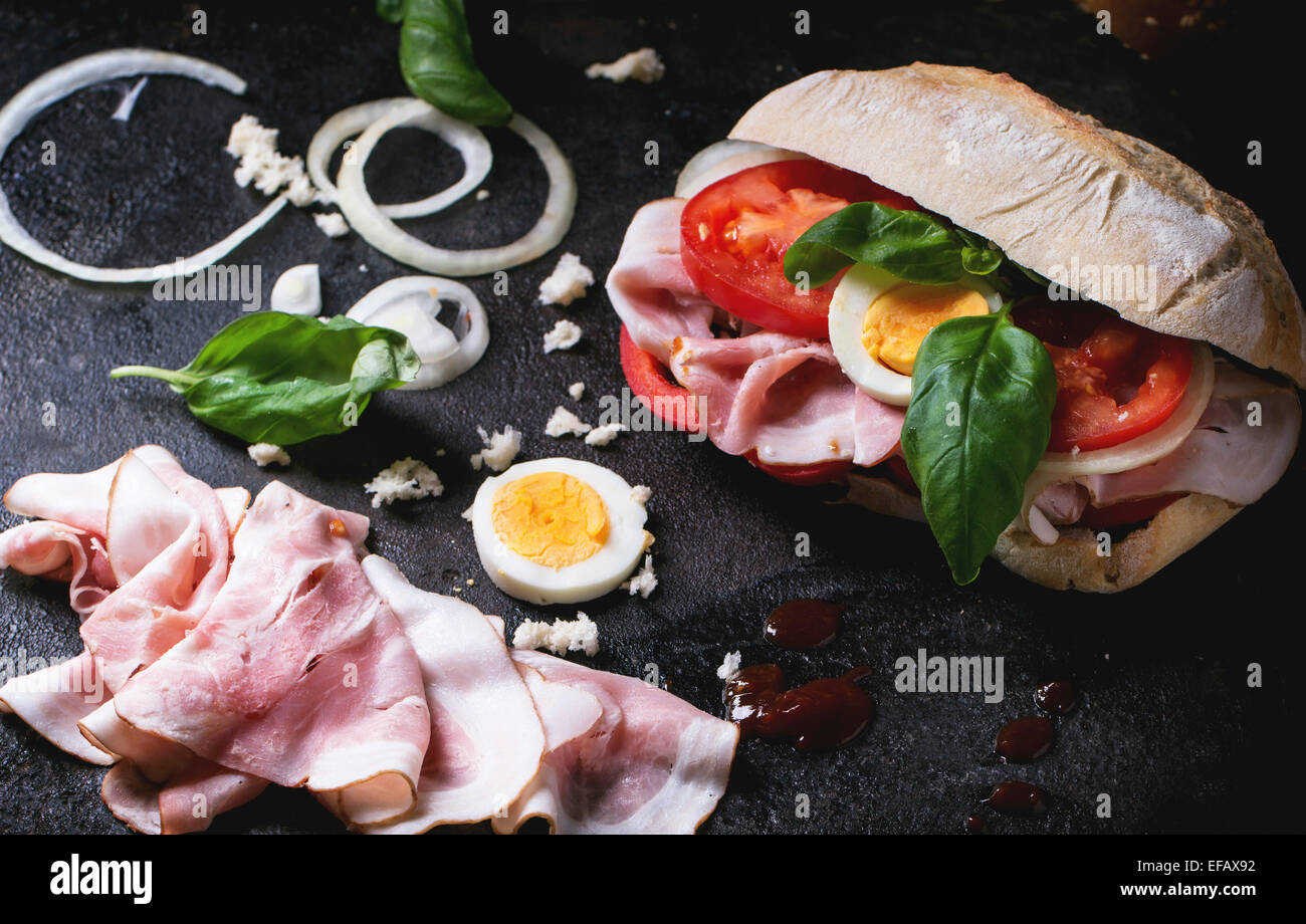 Sandwich mit Schinken, Eiern, Gemüse und Ketchup, serviert mit Pommes Frites auf schwarzem Hintergrund. Serien ansehen Stockfoto
