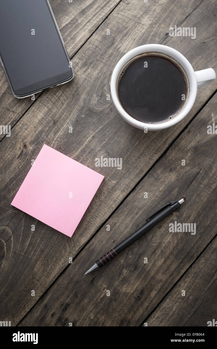 Smartphone mit klebrigen Notizpapier und Tasse Kaffee auf alten Schreibtisch aus Holz. Stockfoto