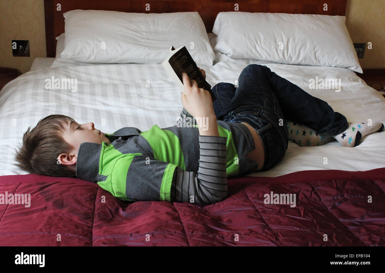 Junge Teenager Buch zu lesen, während auf einem Bett legen Stockfoto