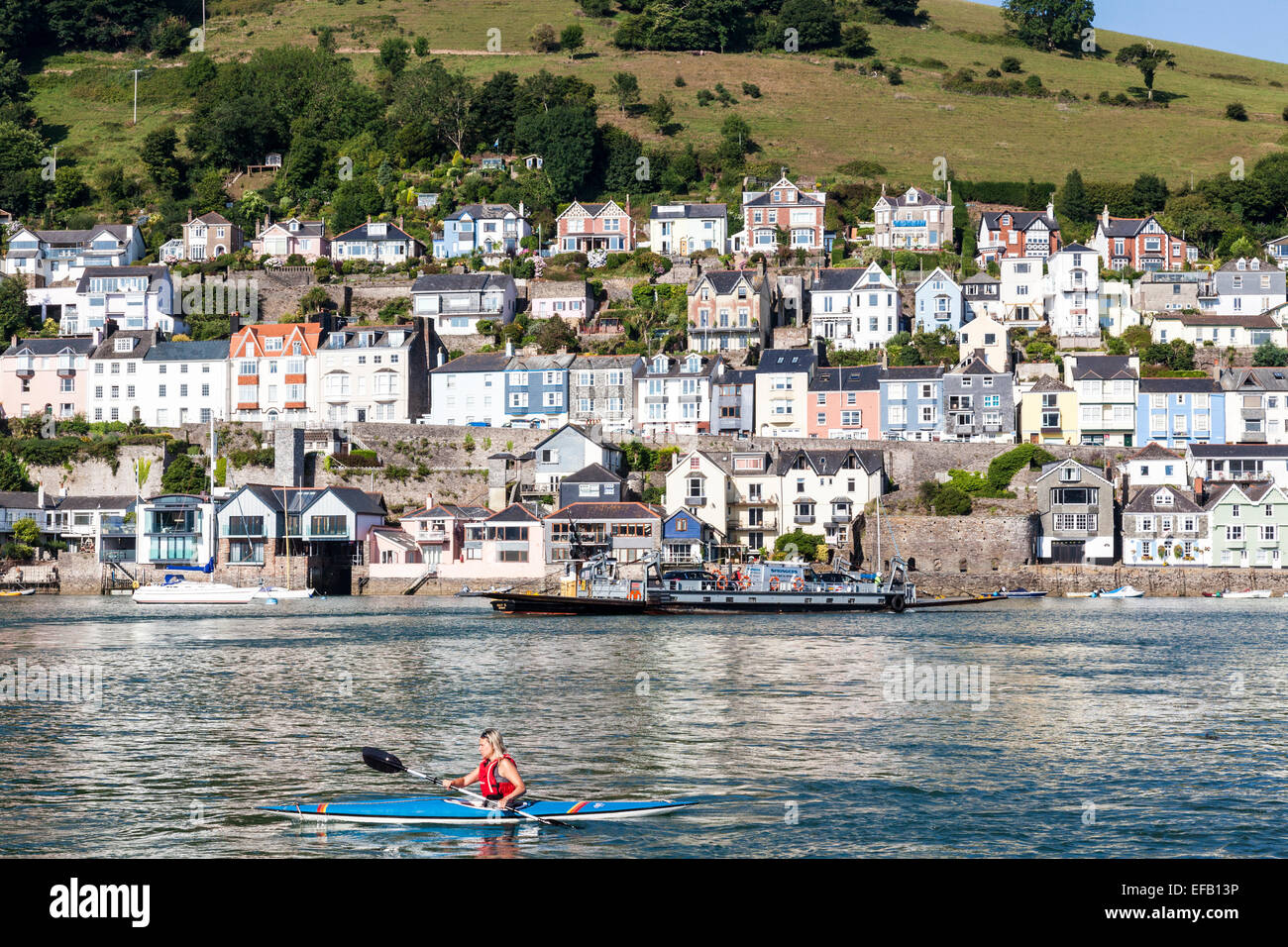 Eine Frau in einem Kajak auf dem River Dart mit Dartmouth Stadt auf dem Wasser Stockfoto
