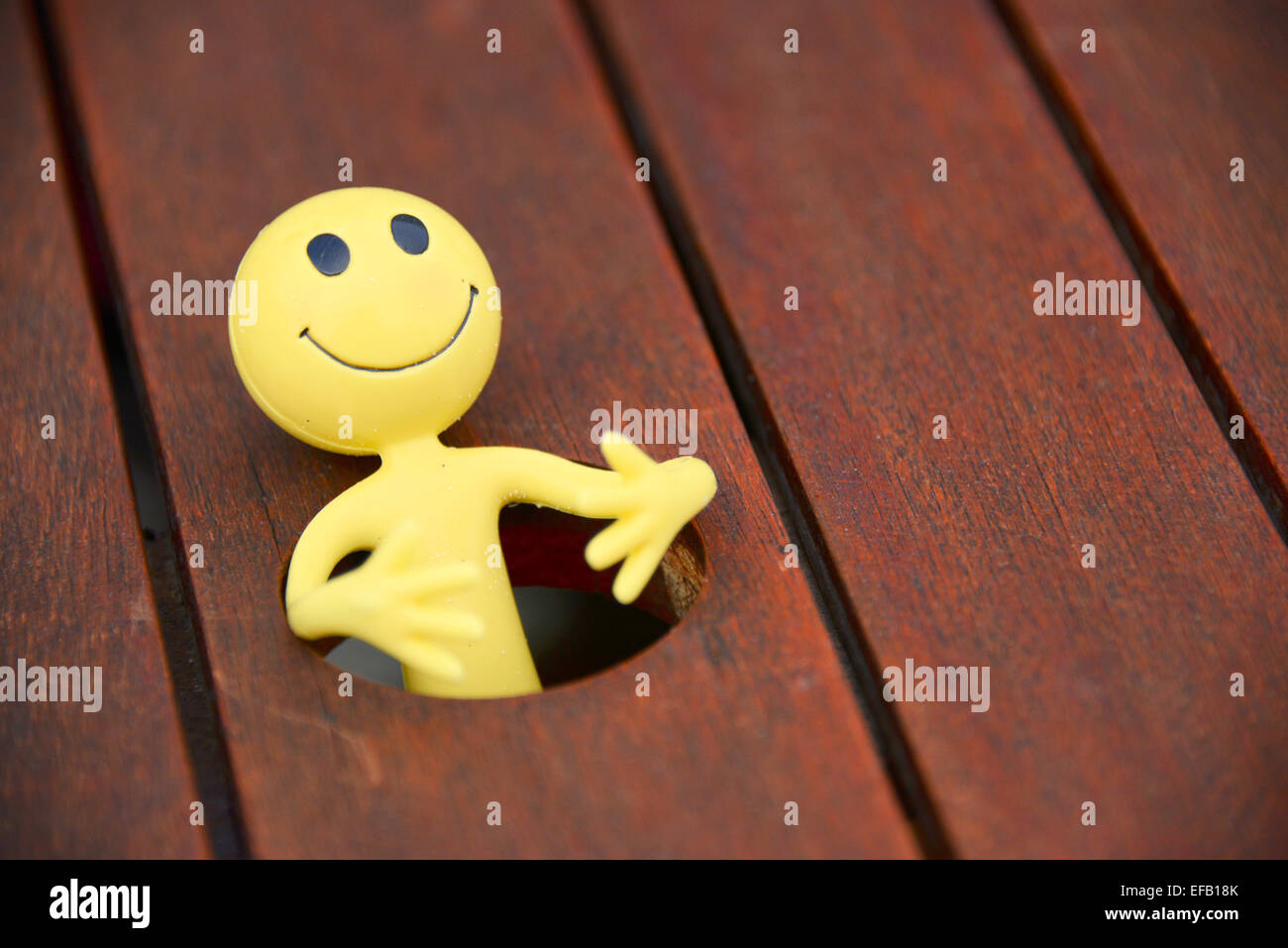 Gelbes Smiley-Mann im Urlaub in den äußeren Hebriden - hat er hier durch das Dach-Loch in einen Terrassentisch gefallen Stockfoto