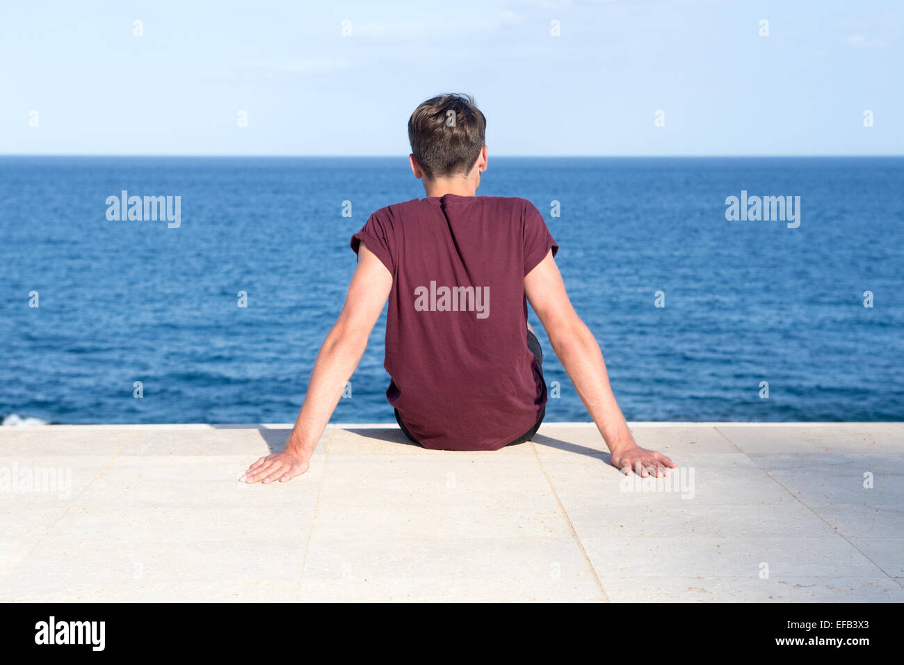 Junger Mann blickt auf das Meer Stockfoto