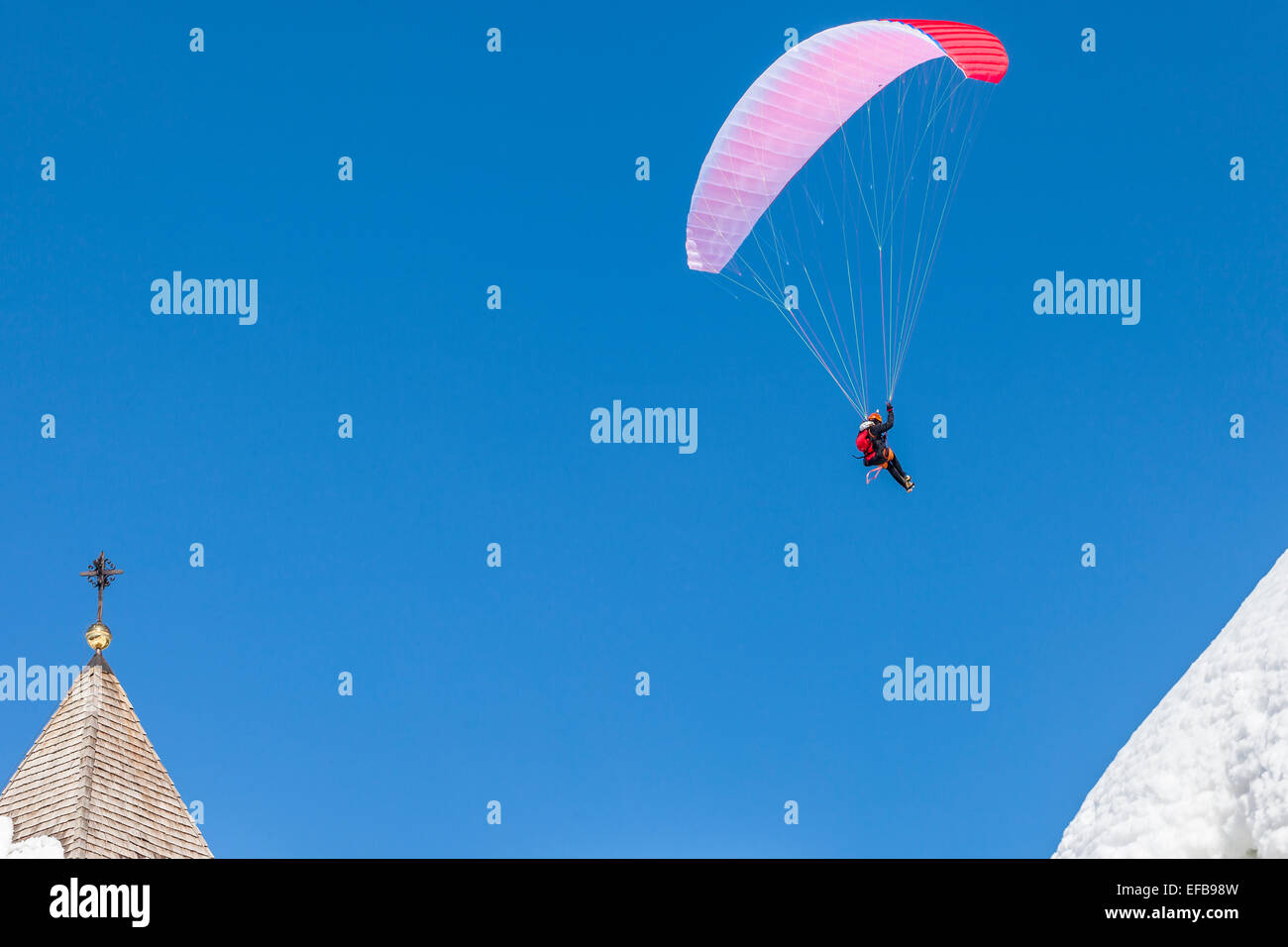 Paragliding an einem Wintertag über einige schneebedeckte Dächer, Tarvisio, Italien Stockfoto