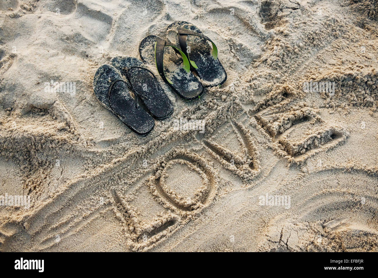 Sand schreiben des Wortes Liebe mit ein paar Sandalen Stockfoto