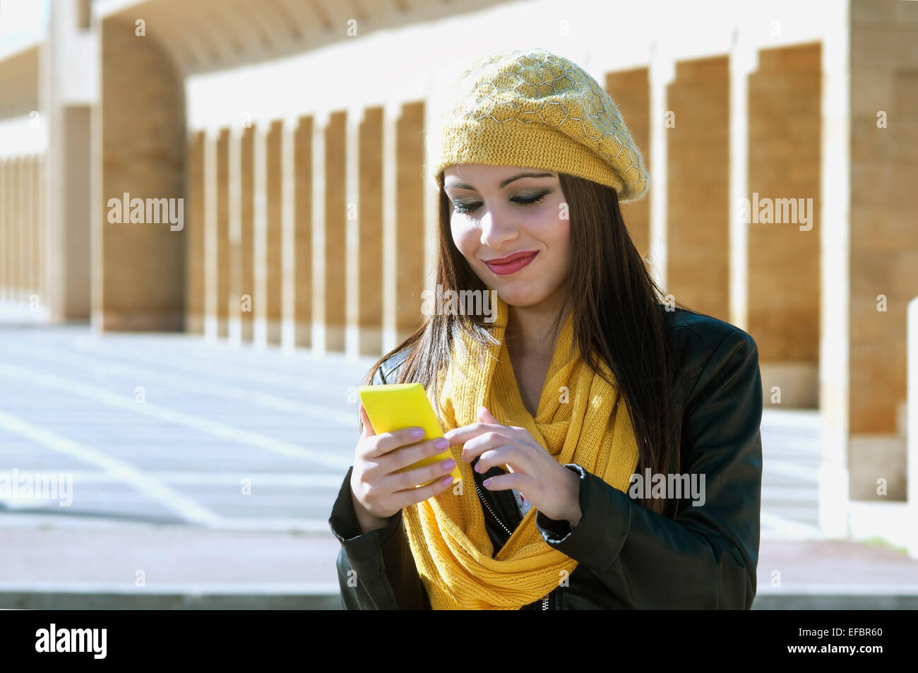 schöne Brünette Mädchen schaut auf sein Handy, eine SMS zu schreiben. modernen urbanen Umfeld Stockfoto