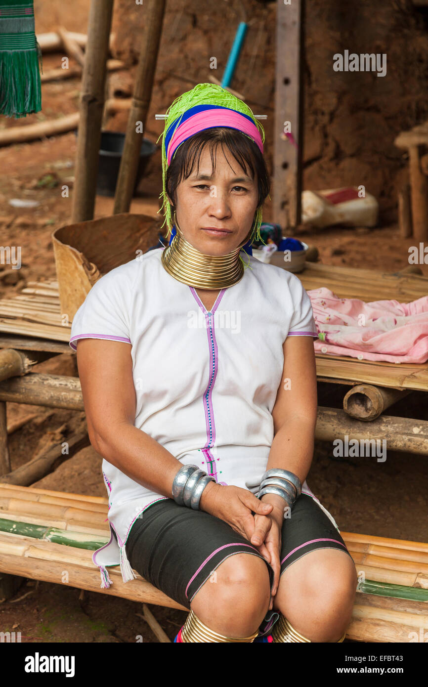 Die jungen Burmesischen Karen lange Hals Frau mit Halsring, eine burmesische Flüchtlinge, die außerhalb einer Lehmhütte in Padong Karen Dorf sitzen, Chiang Rai, Thailand Stockfoto