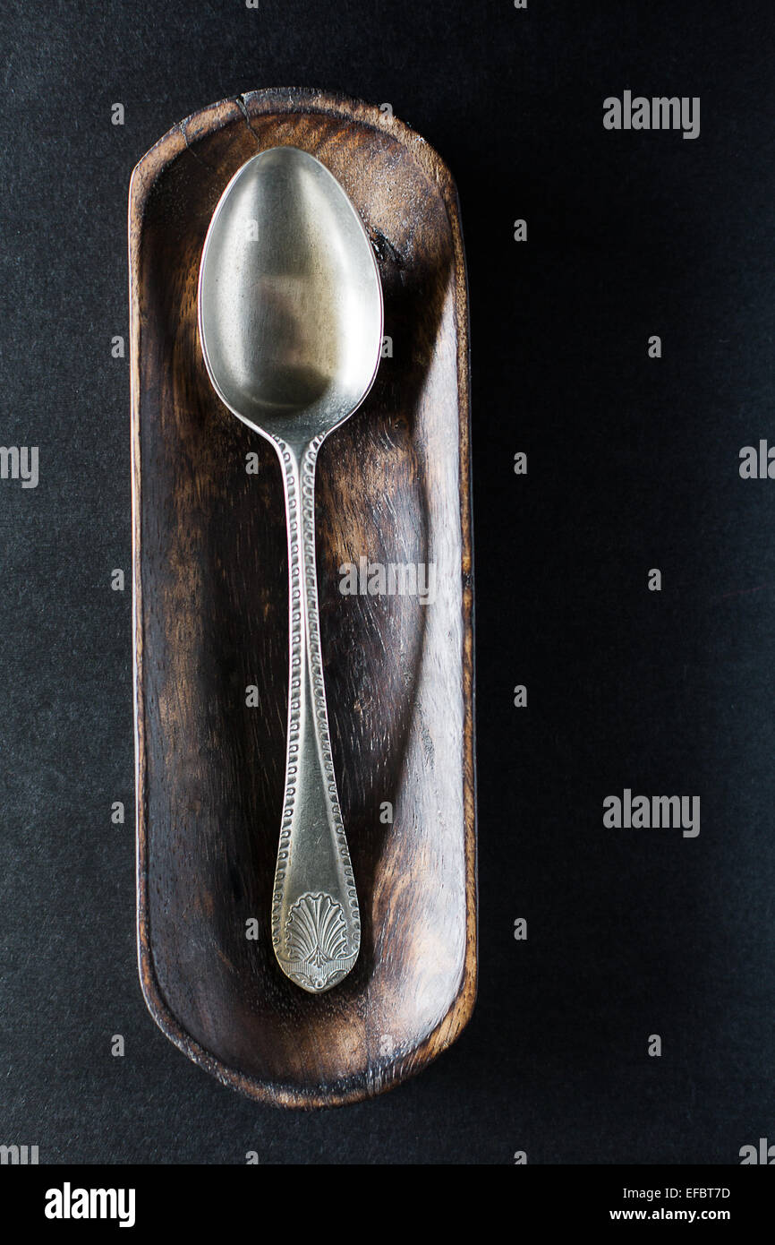Alte vintage Silver Spoon auf kleinen Holz platter auf schwarz Tabelle Stockfoto