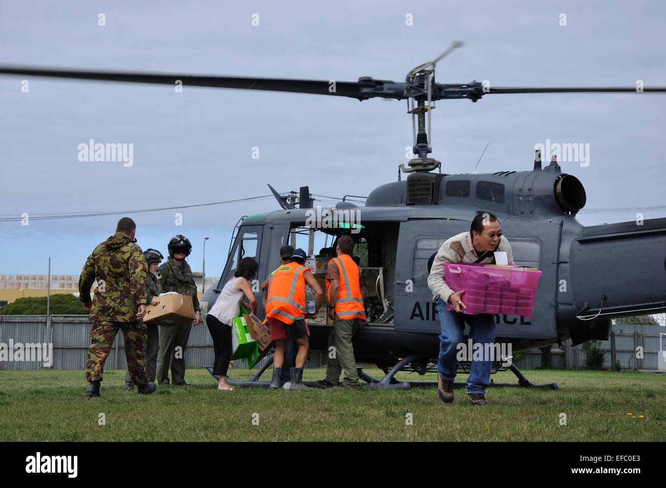 CHRISTCHURCH, NEW ZEALAND, 22. Februar 2011: freiwillige Relief Arbeiter Gerangel um die Versorgung mit Nahrungsmitteln aus einer Luftwaffe Hubschrauber Stockfoto
