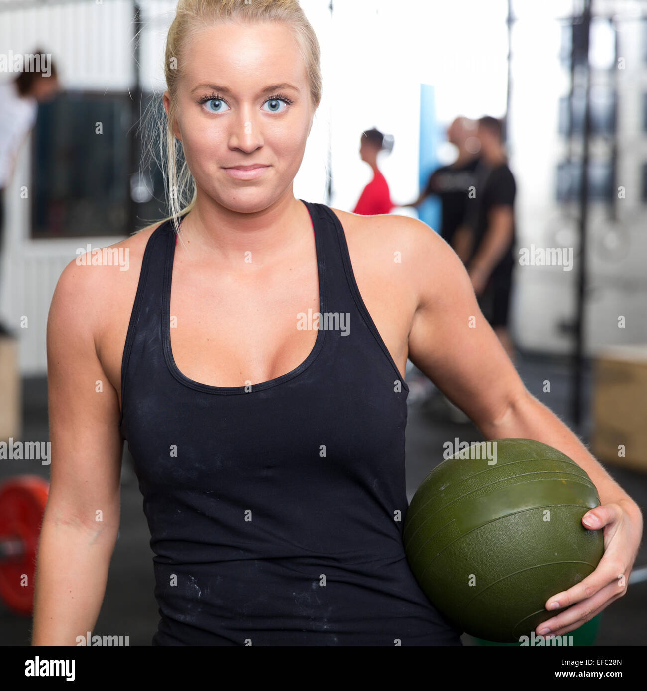 Lächelnde junge Frau mit Slam-Ball im Fitness center Stockfoto