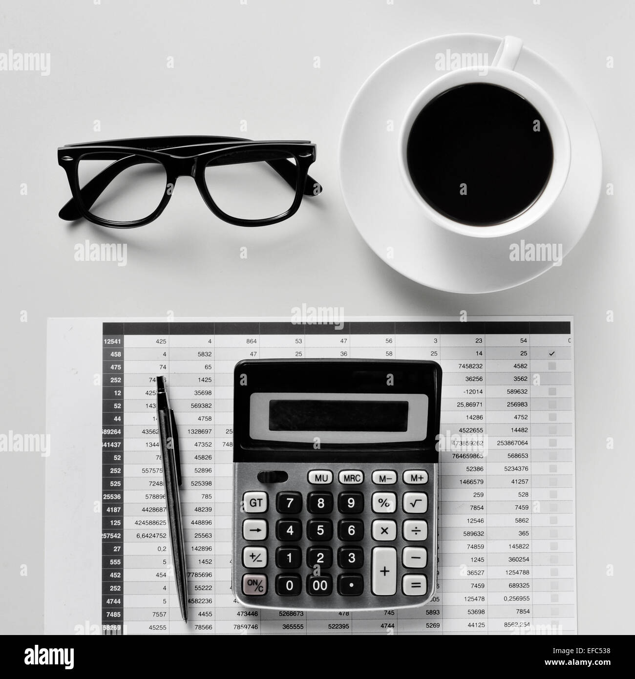 High-Angle Shot von einem Schreibtisch mit einem Rechner, einen Stift, eine Bilanz, Brillen und eine Tasse Kaffee in einem Büro Stockfoto