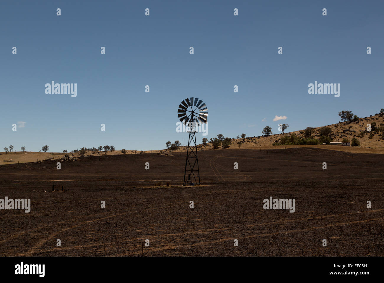 Ein Foto von einer Windmühle im Anschluss an ein Buschfeuer auf einer trockenen australischen Farm im zentralen westlichen NSW. Stockfoto