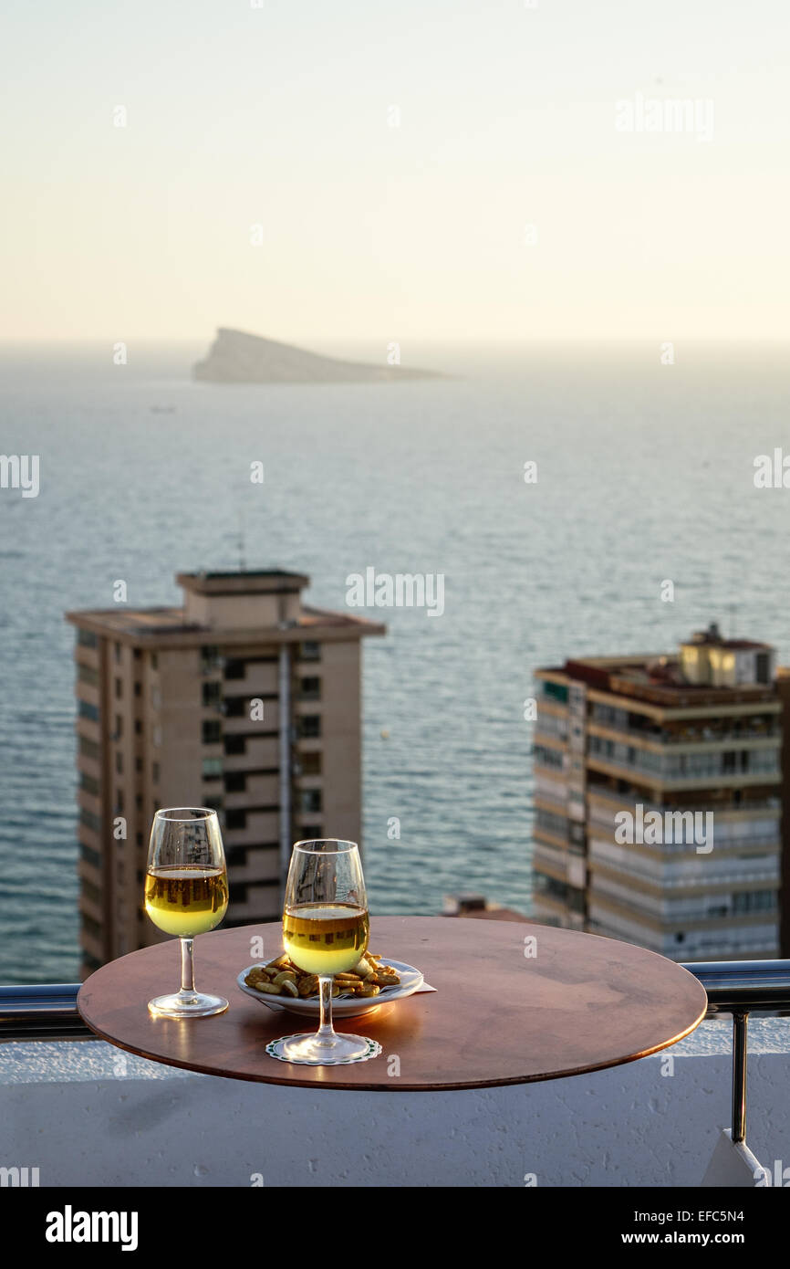 Gläser Weißwein mit Snacks an der Bar auf der Dachterrasse und Blick auf die Pfaueninsel, Benidorm, Costa Blanca, Spanien Stockfoto