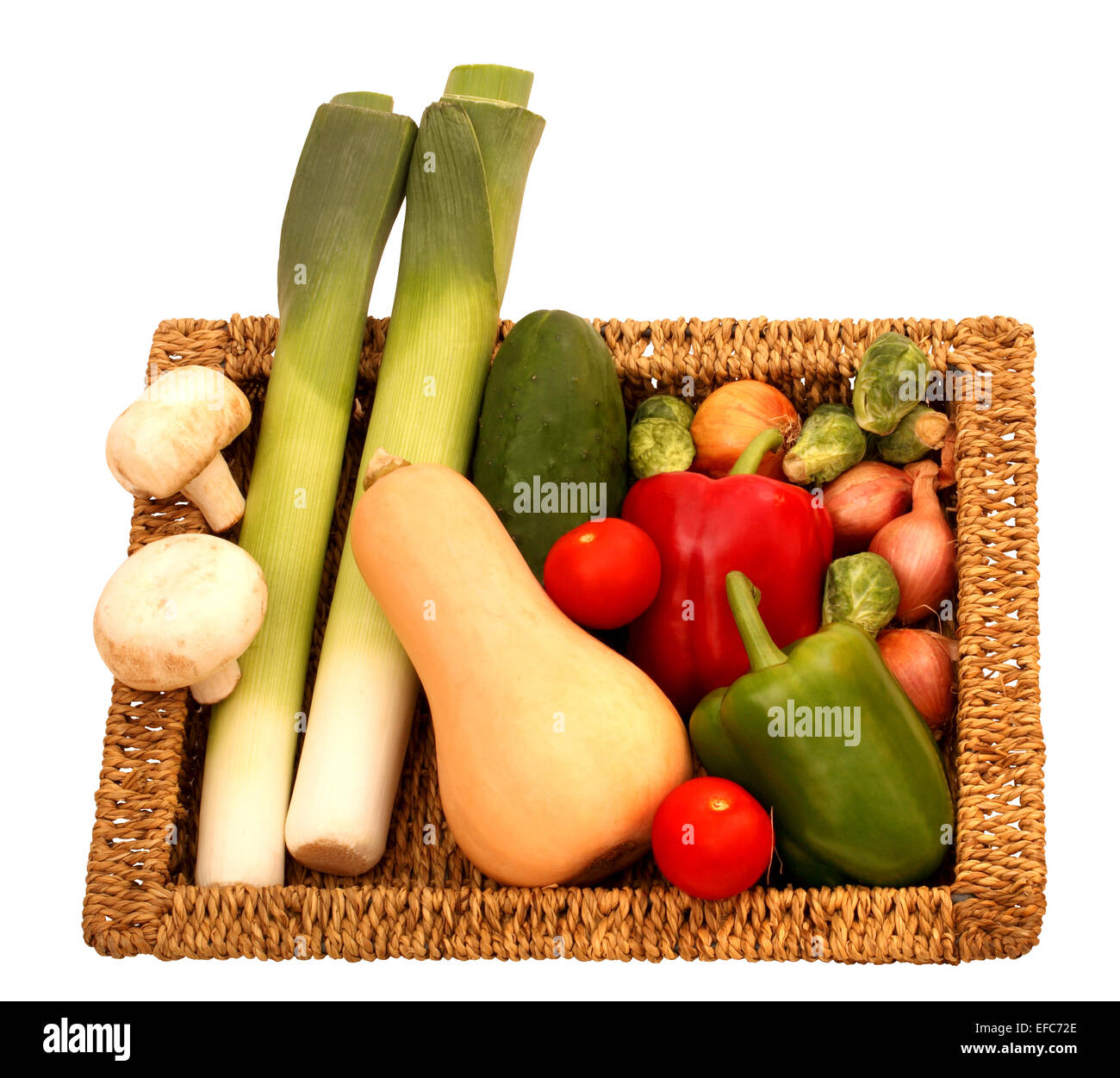 Ein flacher Weidenkorb voll mit selbst angebautem Gemüse auf weißem Hintergrund Stockfoto