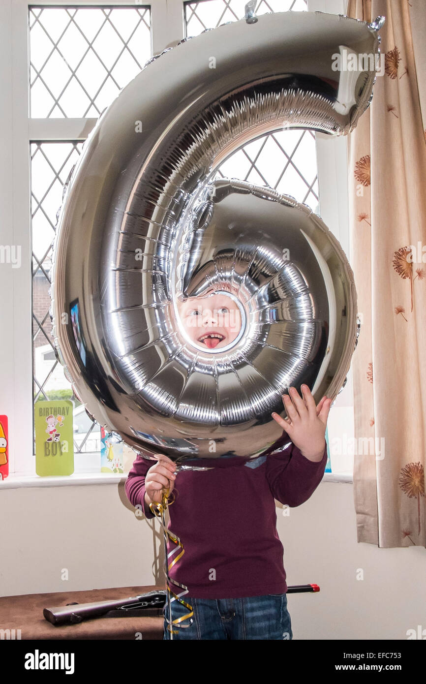 Junge feiert sechsten Geburtstag mit riesigen Ballon geformt Nummer sechs Stockfoto