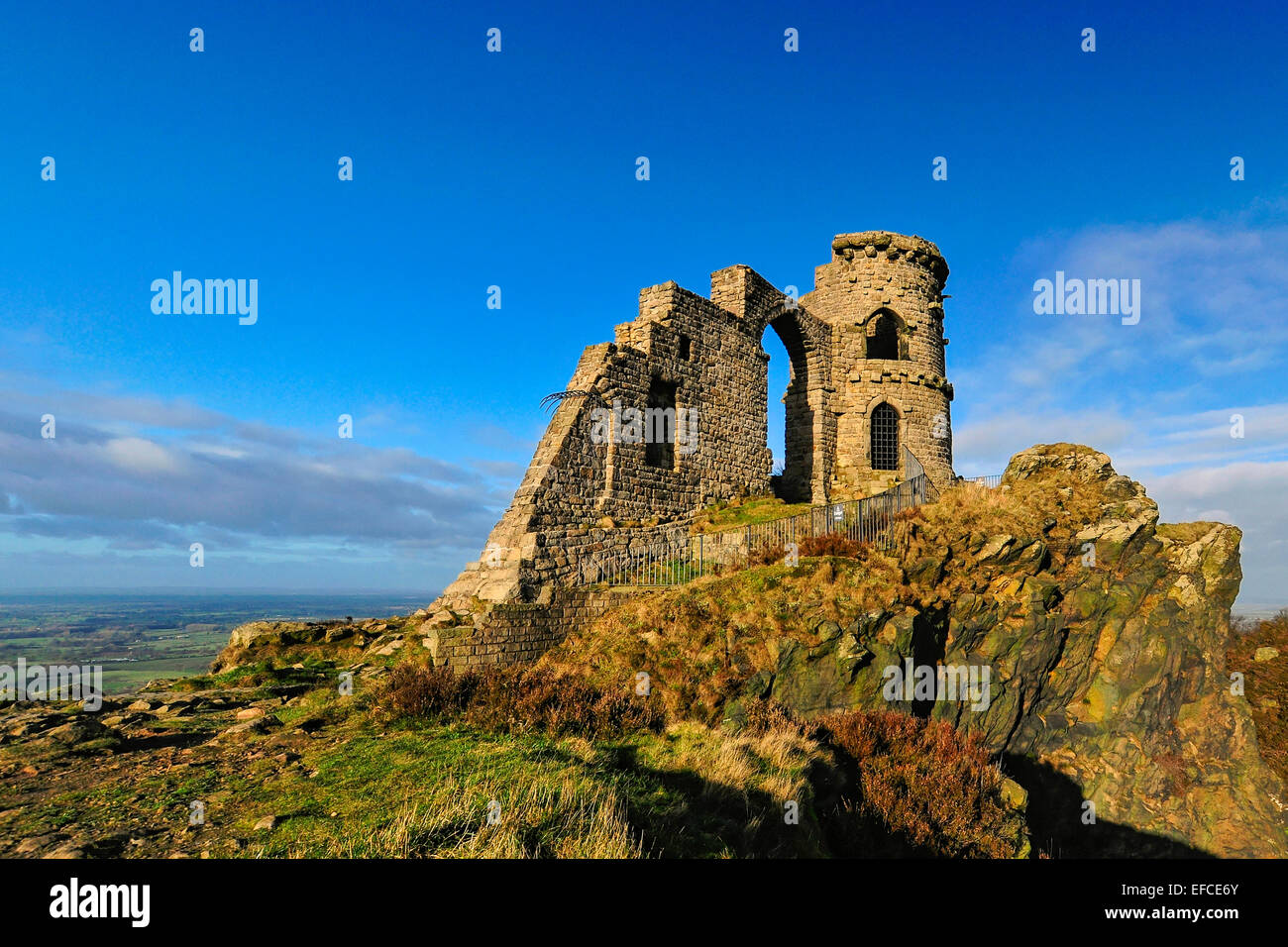Mow Cop Burg, eine Torheit an der Grenze von Cheshire-Staffordshire; Landschaft im Hintergrund; blauer Himmel mit weißen Wolken. Stockfoto