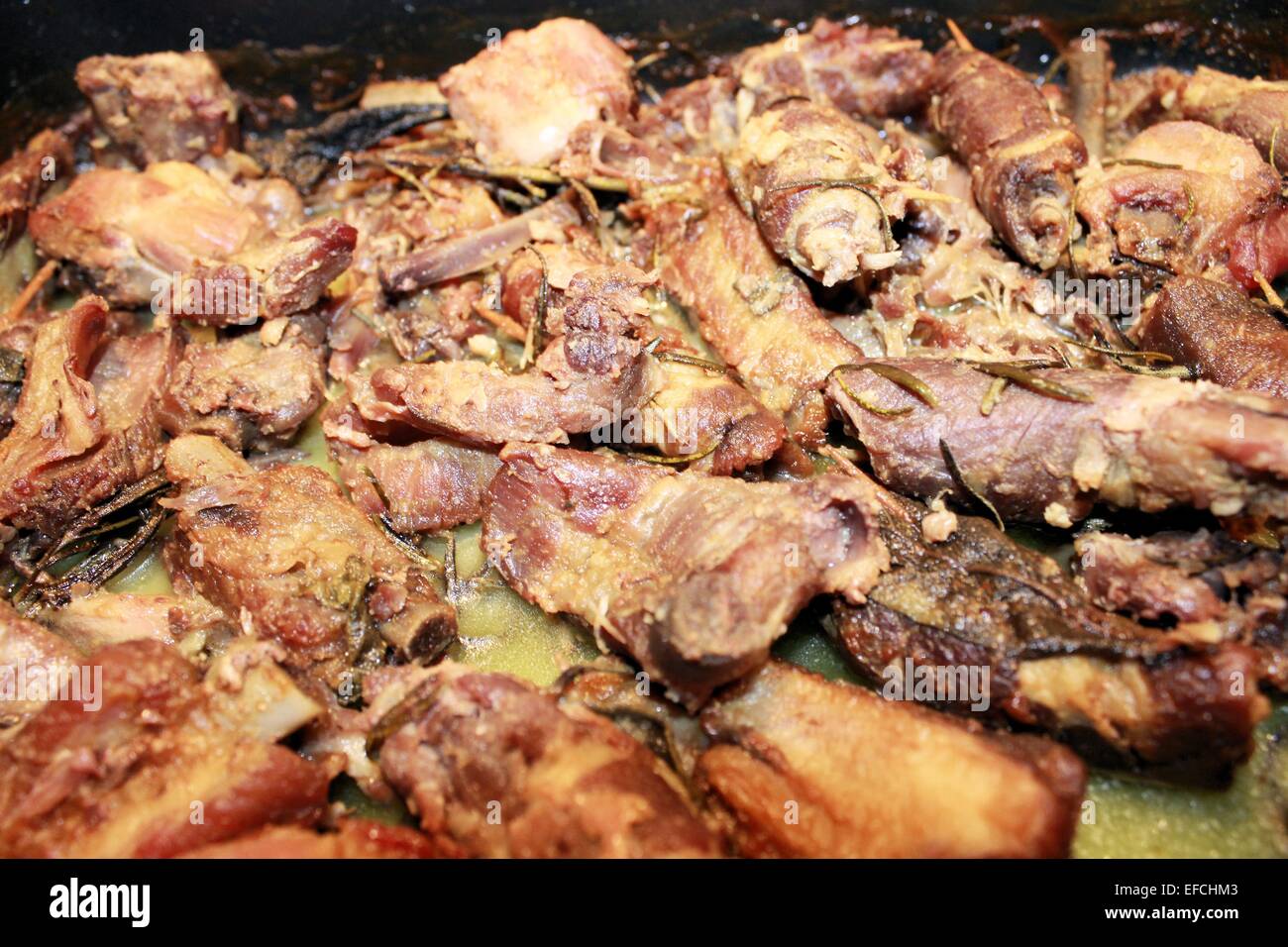 Fleischstücke mit Salbei und Rosmarin im Ofen gegart Stockfoto