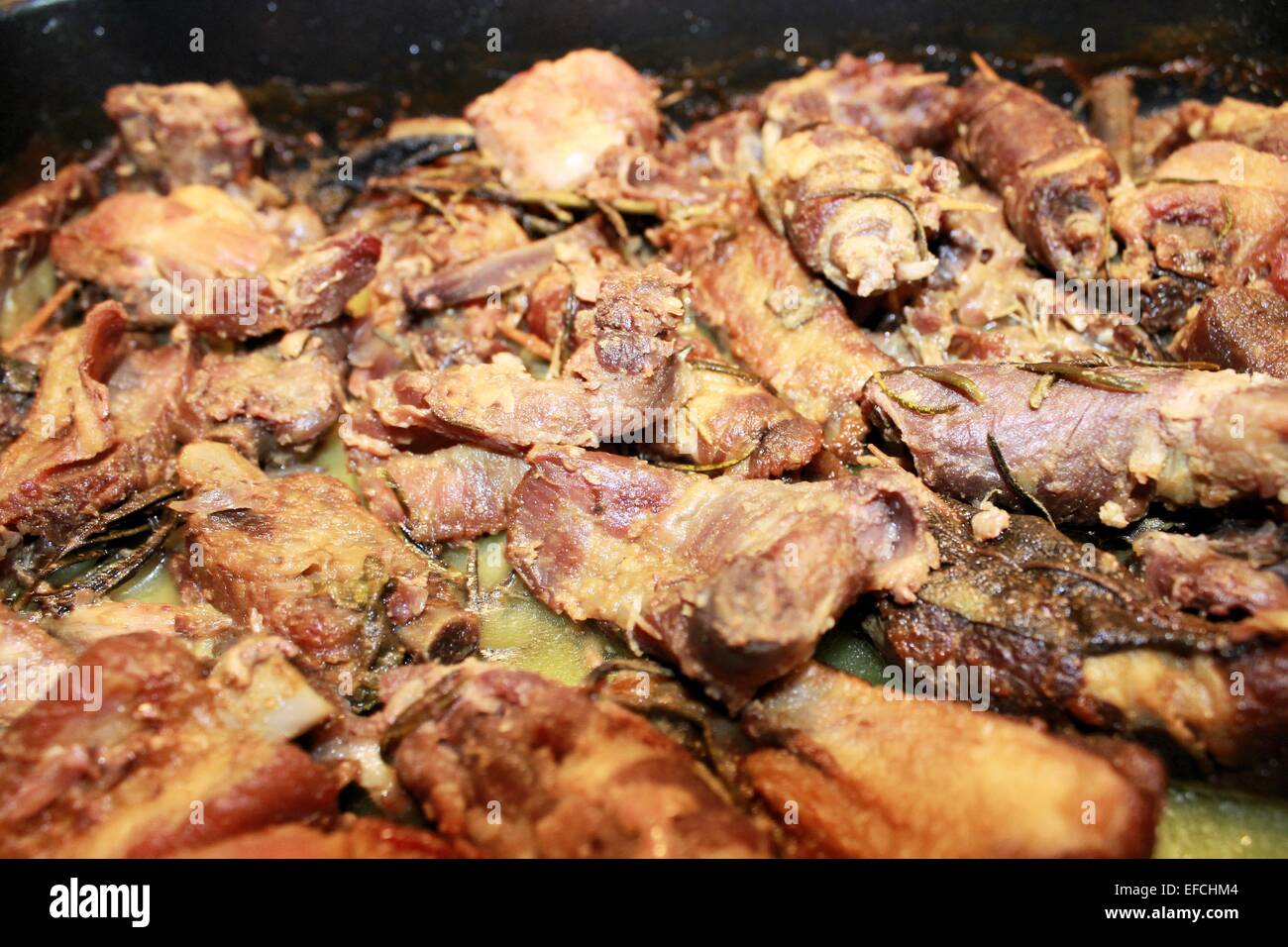 Fleischstücke mit Salbei und Rosmarin im Ofen gegart Stockfoto