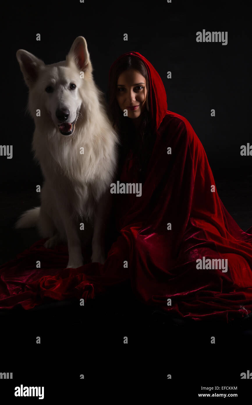 Frau trägt eine rote Haube posiert im Studio mit ihrem Hund Stockfoto