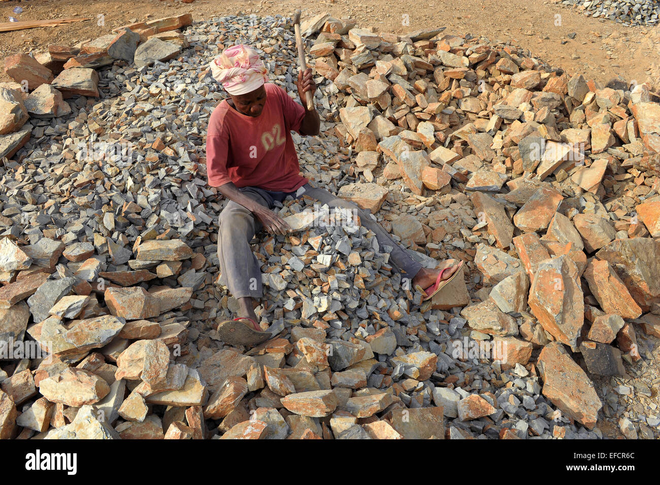 Eine Frau bei der Arbeit, die Felsen zu brechen, in Kies in einem Steinbruch in der Nähe von Accra, Ghana, Westafrika. Stockfoto