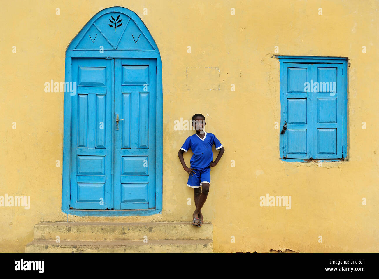 Ein Junge in blau vor einer Kirche in Esiam, Ghana, Westafrika. Stockfoto