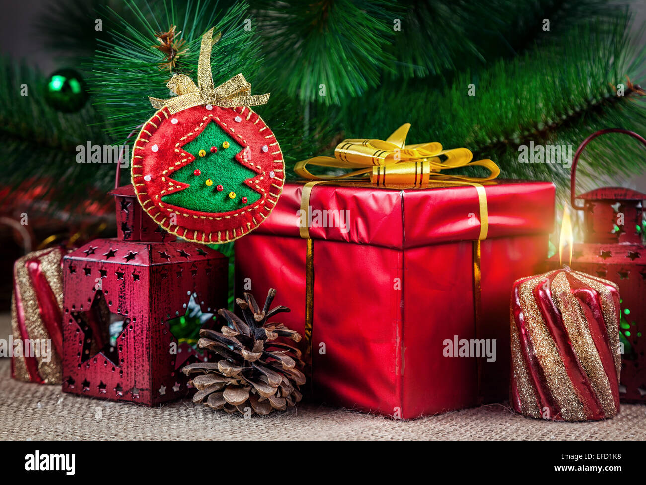 Handgemachte Weihnachtskugel aus Filz in der Nähe der Weihnachtsbaum, rotes Feld, Laterne, Kegel und Kerze Stockfoto