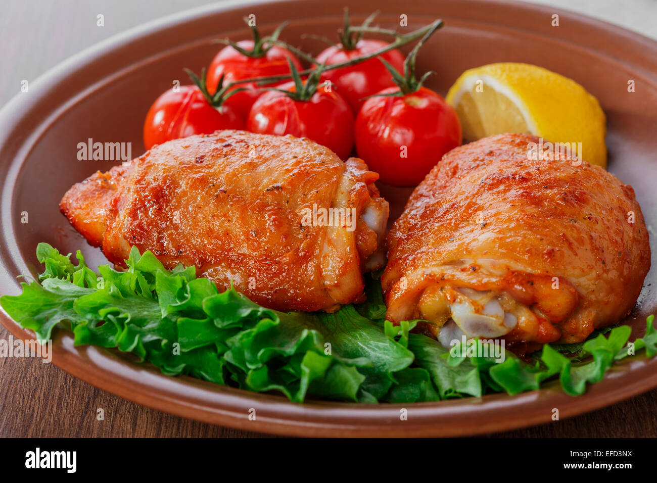 gebackene Hühnerkeule mit Cherry-Tomaten und Zitrone Stockfoto