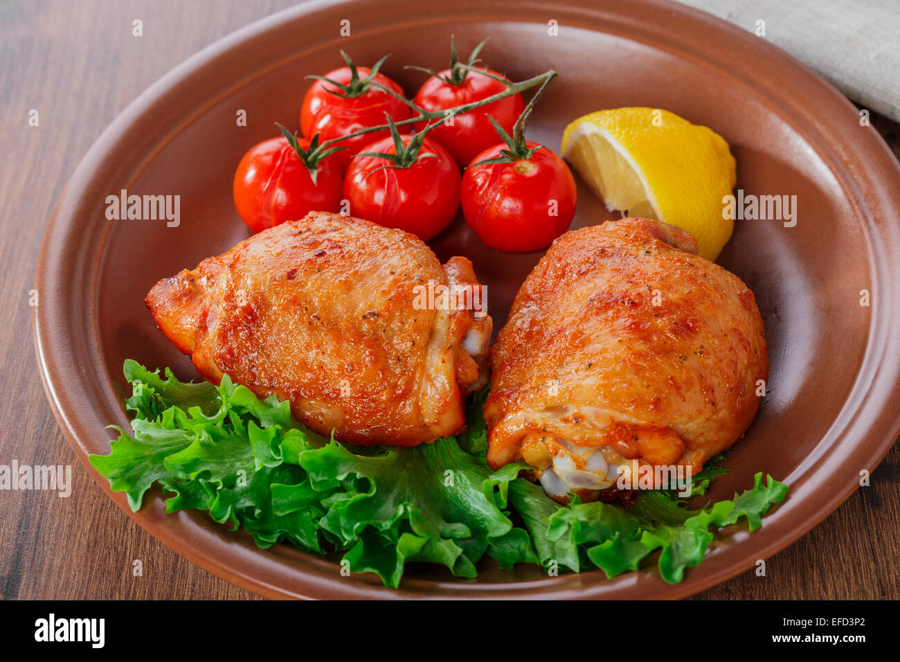 gebackene Hühnerkeule mit Cherry-Tomaten und Zitrone Stockfoto