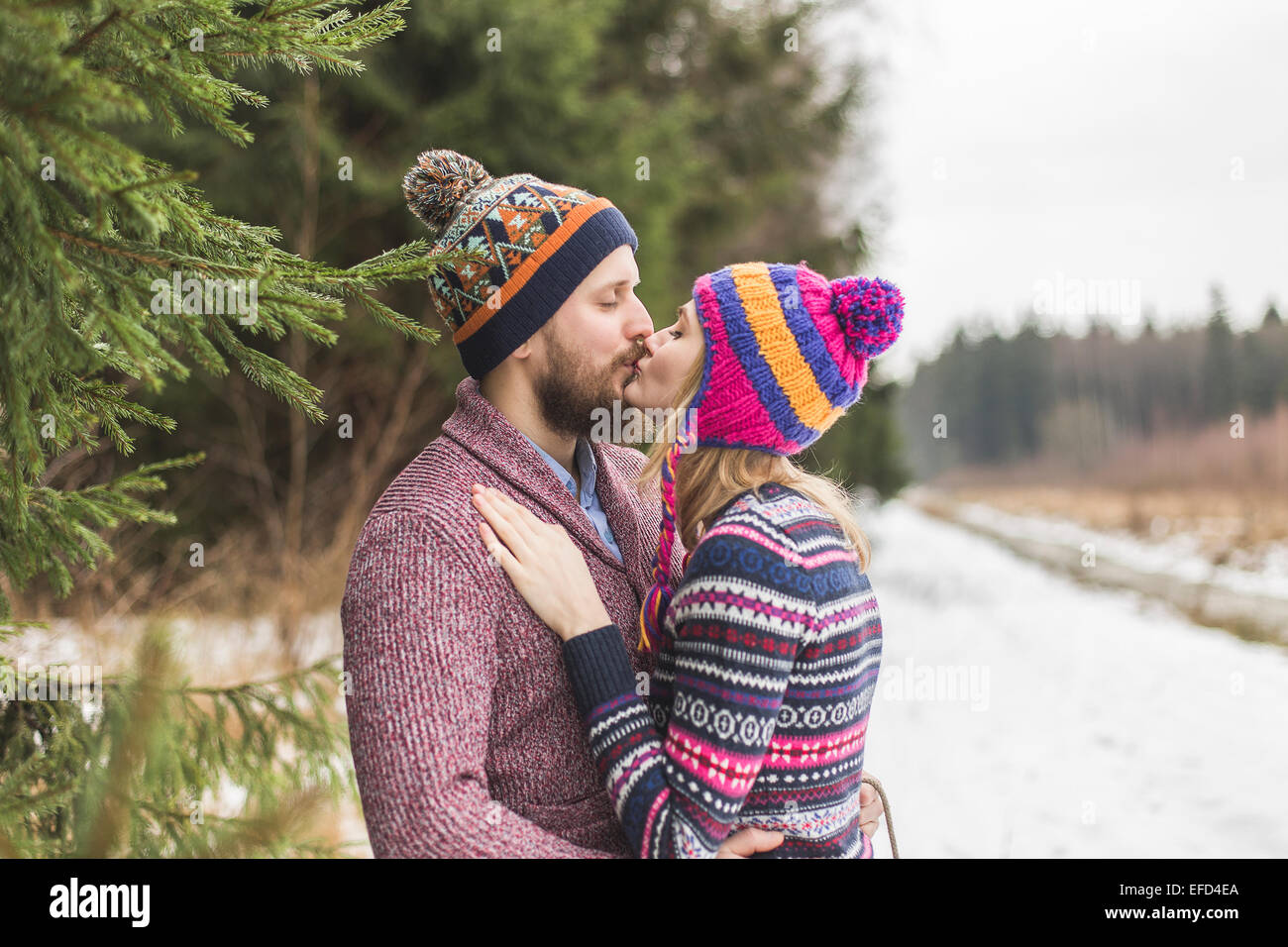 Junge Gartenpfleger küssen im Winterwald Stockfoto