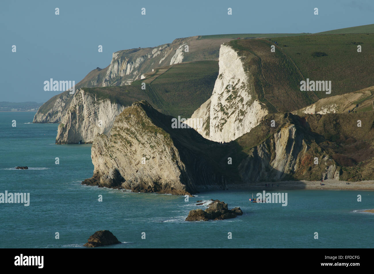 Durdle Dor. eine Kalkstein-Felsen und Angeln Boot in Mann O'War Cove, mit der Kreide, Bat es Kopf und weiße Nothe Bucht hinaus. Stockfoto