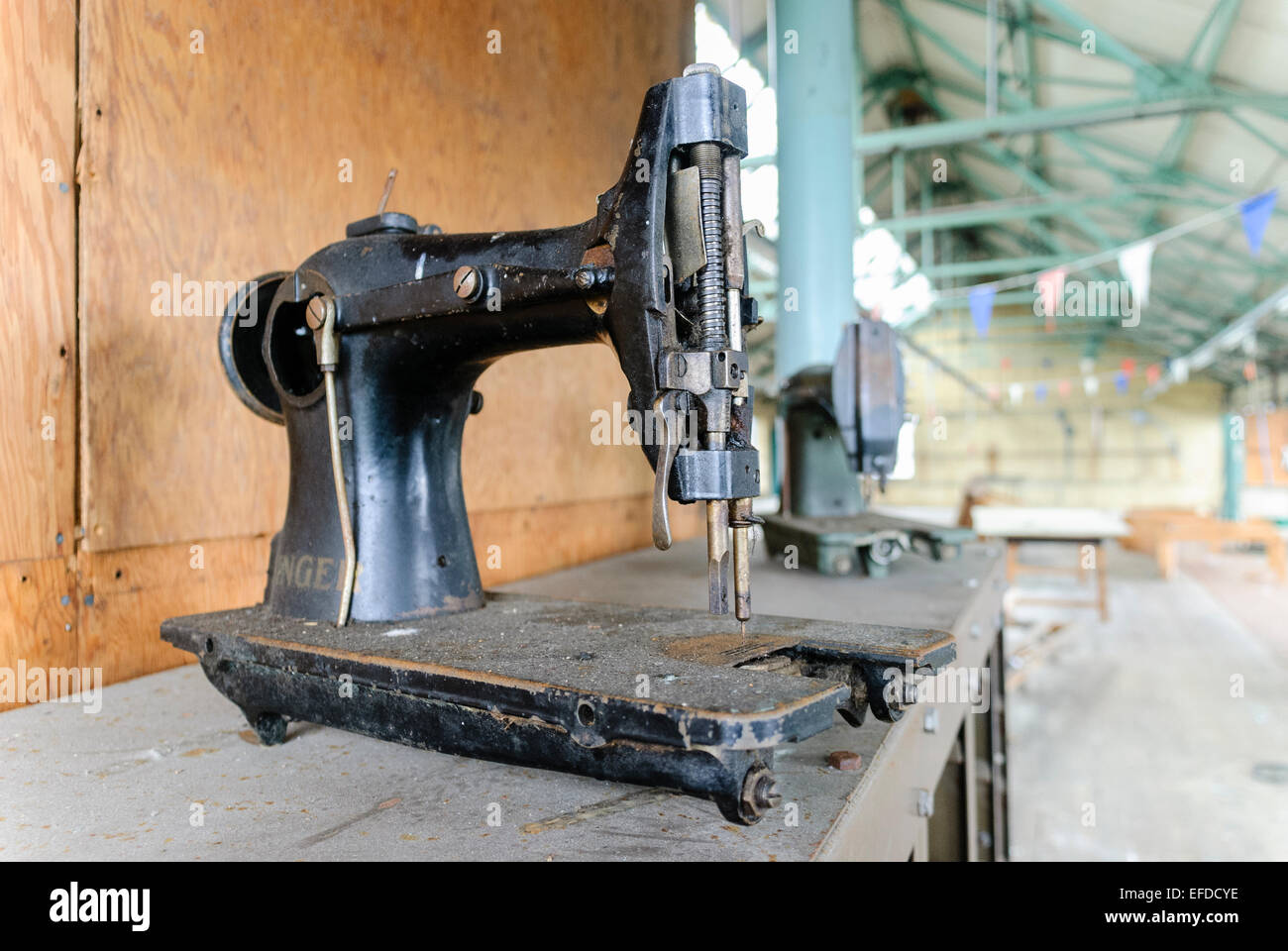 Eine sehr alte mechanisch angetriebenen Singer Industrienähmaschine in einer verlassenen Fabrik. Stockfoto