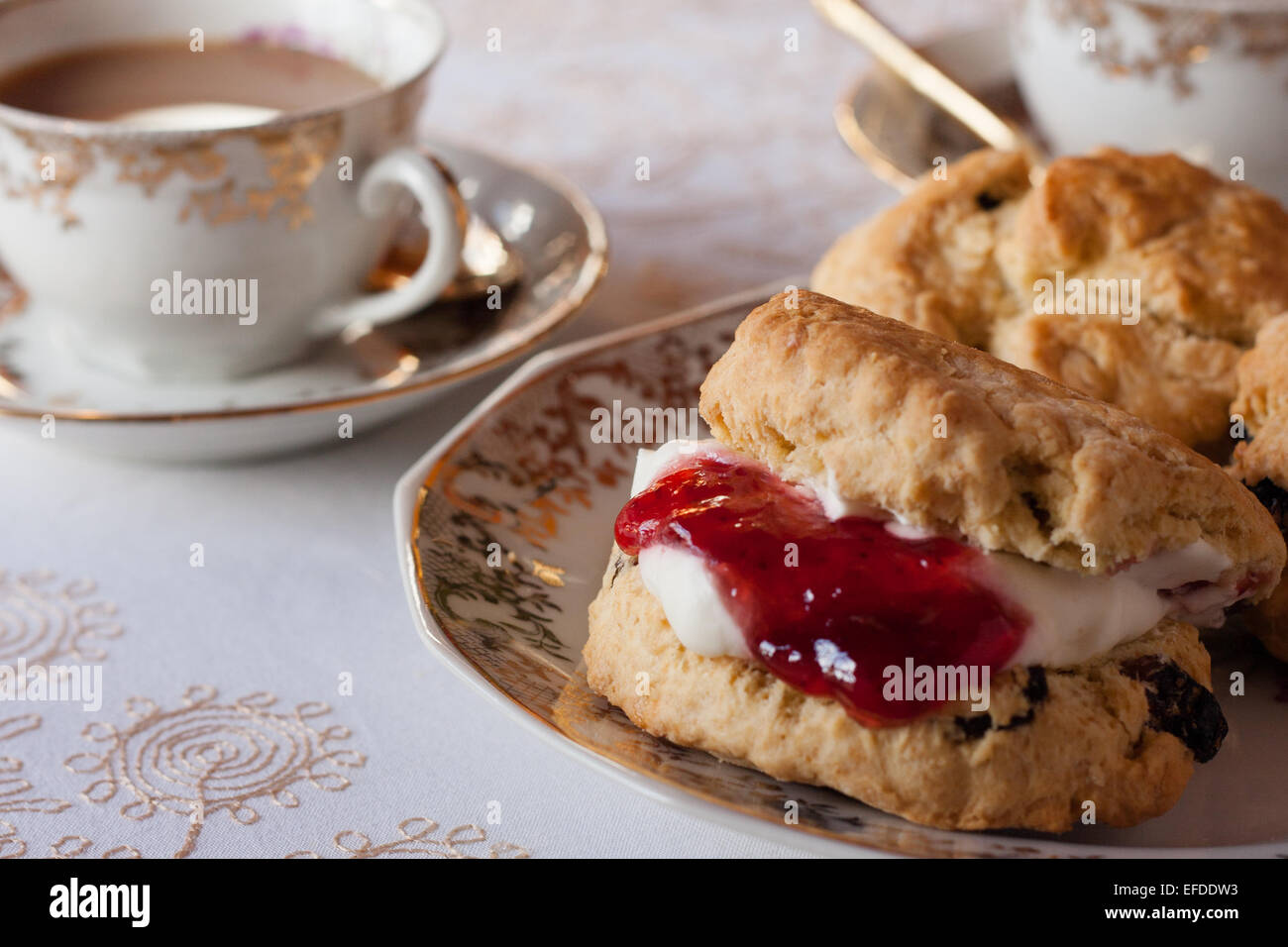 Ein Tisch für traditionelle englische Creme Tee. Marmelade und Gebäck mit einer Tischdecke und feines Porzellan mit Tageslicht Stockfoto