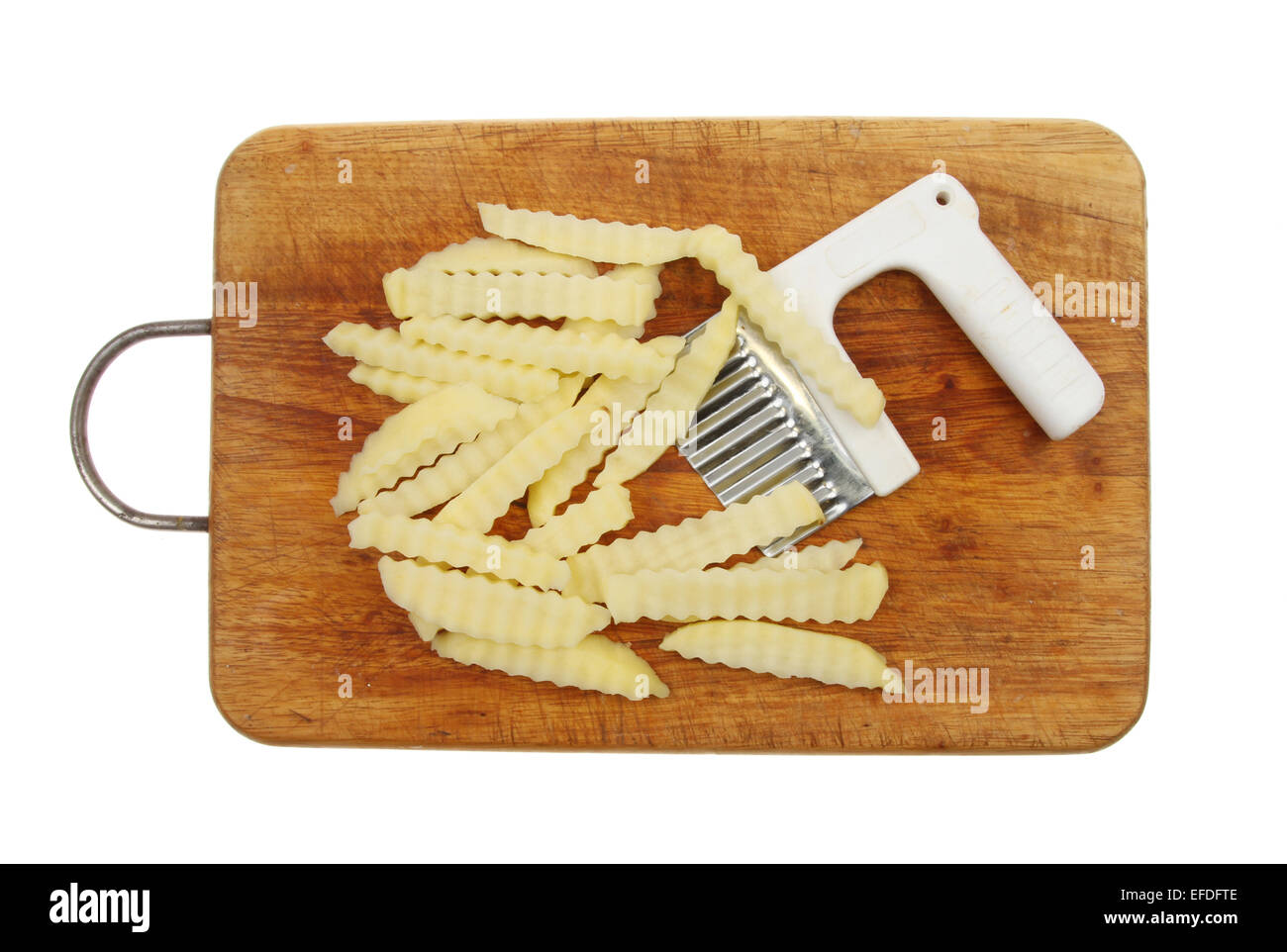 Crinkle geschnittenen rohen Kartoffel-Chips mit Cutter auf einem Holzbrett isoliert gegen weiß Stockfoto