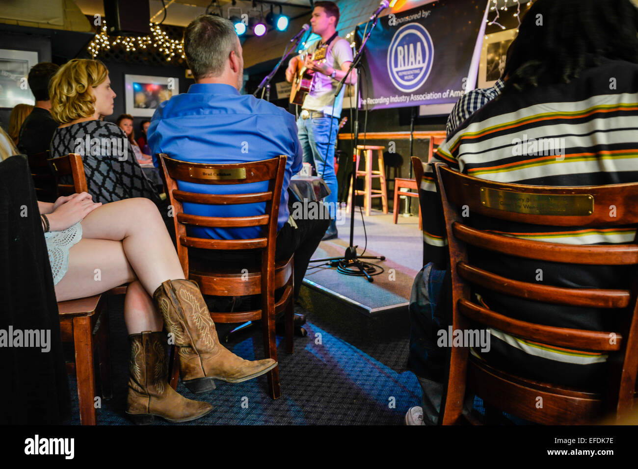 Songwriter tritt mit dem kurzen Rock der Frau und den Cowboy-Stiefeln im legendären Blue Bird Café in Nashville, TN, USA, auf der Bühne auf Stockfoto