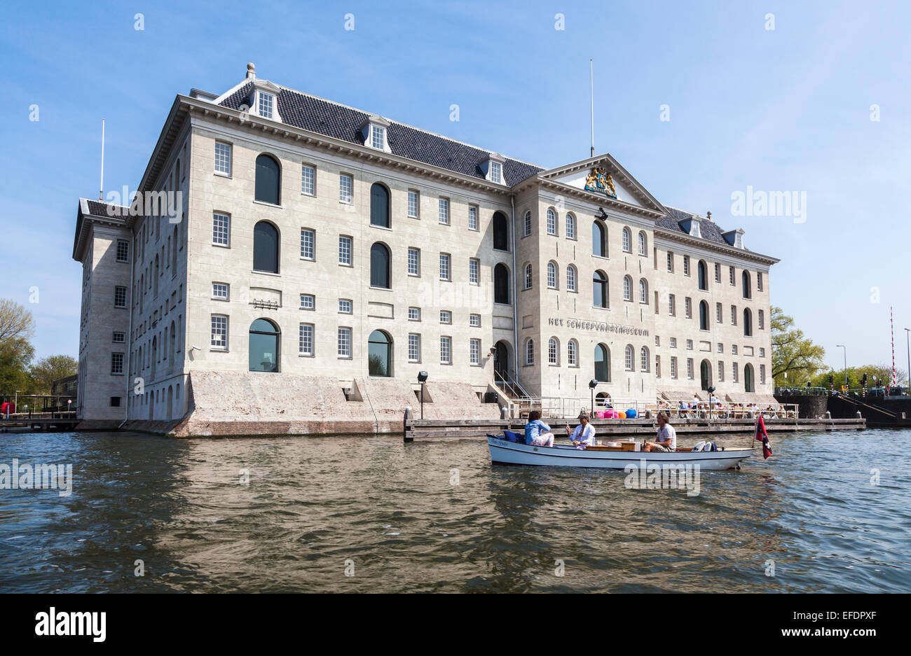 National Maritime Museum (Het Scheepvaartmuseum) in Amsterdam, Holland an einem sonnigen Tag mit blauem Himmel, betrachtet aus dem Kanal Stockfoto