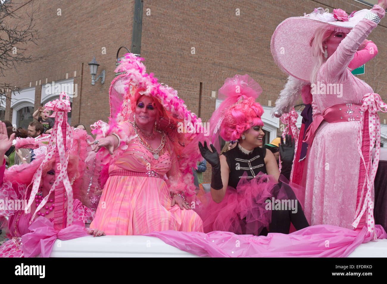 Rüschen kostümierte Damen in Rosa mit rosa Haut fahren und winken den Zuschauern während der Asheville, NC Karneval Parade Stockfoto